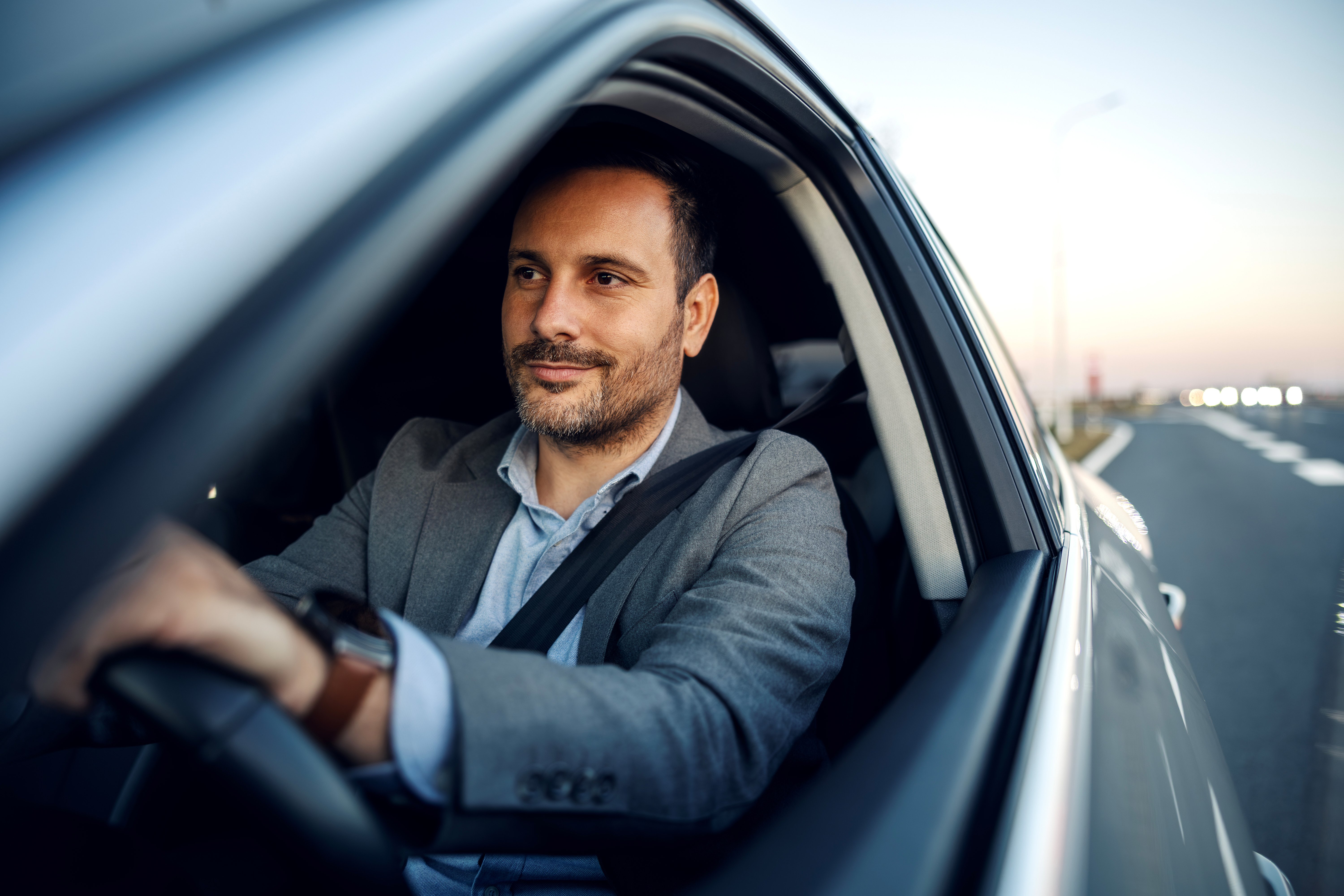Selbstbewusster Geschäftsmann fährt Auto und genießt den Roadtrip