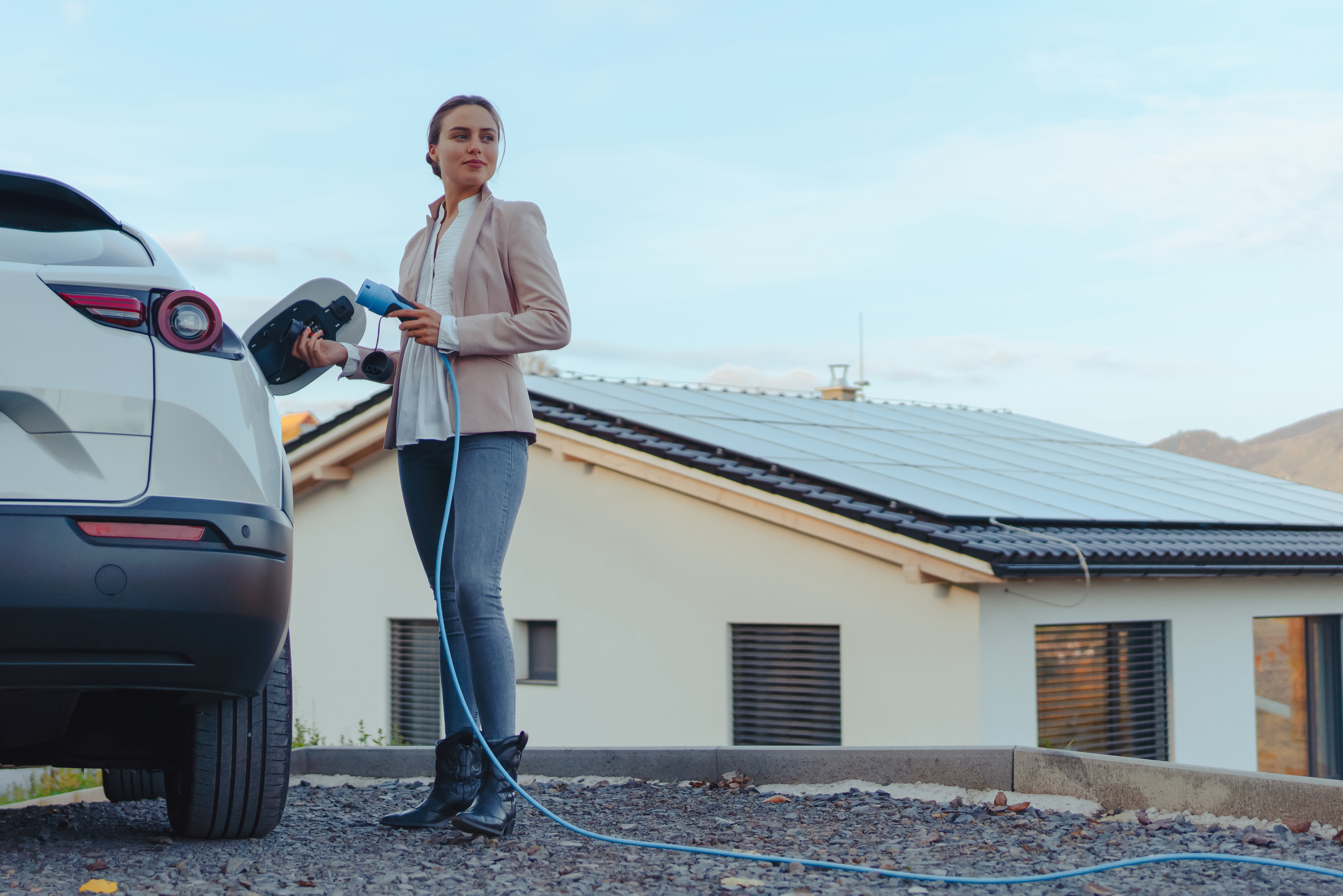Eine Frau profitiert vom PV-Überschussladen und lädt ihr Elektroauto mit kostenlosem Solarstrom vom eigenen Dach.