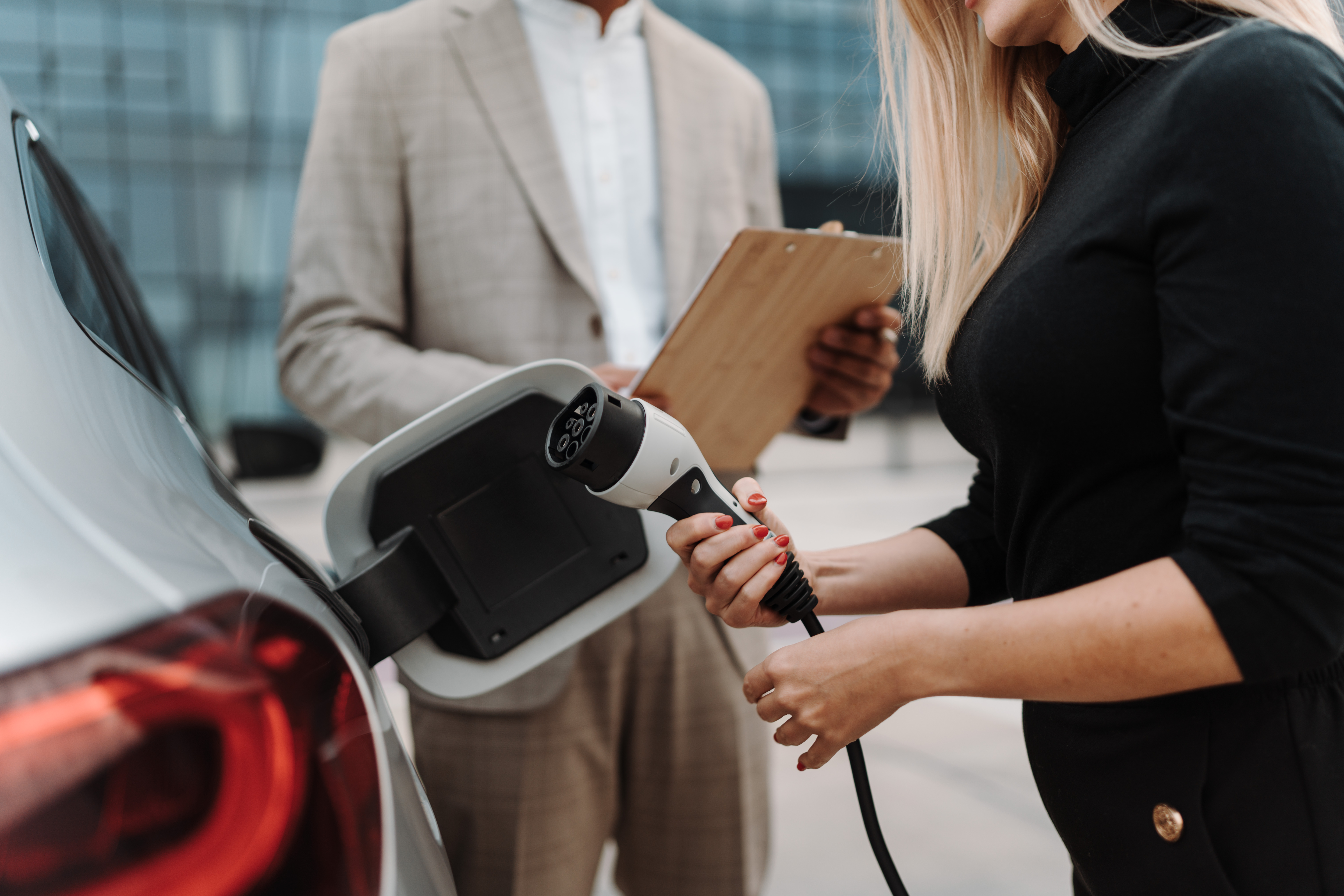 Verkäufer zeigt Kunden den Ladevorgang eines Elektroautos